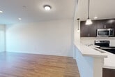 This well-appointed 2-bedroom, 2-bathroom residence at 4552 Lincoln Ave in Cypress, CA offers a clean, modern aesthetic throughout. Warm wood-style flooring runs continuously across the single-level floor plan, creating a cohesive and inviting atmosphere. The open-concept kitchen is a standout feature, showcasing rich dark cabinetry, white quartz countertops, a breakfast bar peninsula with elegant pendant lighting, and a full suite of stainless steel appliances including a French door refrigerator, electric range, and built-in microwave. The kitchen flows naturally into the living area, which is bright and open with recessed lighting. A hallway connects the bedrooms and bathrooms, with the generously sized primary bedroom offering ample space and access to a dedicated closet. The second bedroom provides natural light through a window with blinds. Both bathrooms are finished with dark wood vanities, white countertops, large mirrors, and tub-shower combinations. Additional highlights include a private balcony, a dedicated closet, and consistent recessed and pendant lighting throughout. The overall design is clean and contemporary, making this a comfortable and functional home in Cypress.