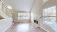 Located at 2802 Cheval St in Orlando, FL, this multi-level home spans three floors and offers a well-designed layout with 2 bedrooms, 2 bathrooms, and a versatile upper loft. The main living level serves as the heart of the home, highlighted by a soaring vaulted ceiling in the open living room that creates an airy, spacious atmosphere. A tile-surround fireplace with a classic white mantel anchors the room, complemented by light hardwood-style flooring and large windows that invite abundant natural light. The kitchen opens directly to the living area via a peninsula counter with a built-in sink, white cabinetry, light quartz-style countertops, and stainless steel appliances. The bedrooms are carpeted and well-proportioned, each featuring ceiling fans and natural light. The primary bedroom is served by a dedicated bathroom with white vanity cabinetry, quartz countertops, and a soaking tub, as well as a walk-in closet with wire shelving. A second full bathroom mirrors the same clean, modern finishes. The top floor hosts a cozy loft space with vaulted ceilings and a ceiling fan, accessed by a white-railed staircase — ideal as an office or additional lounge area. Throughout, neutral tones and consistent finishes create a cohesive, move-in ready aesthetic.