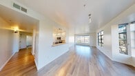 Located at 280 Fell Street in San Francisco's vibrant Hayes Valley neighborhood, this 2-bedroom residence offers a thoughtfully designed single-floor layout with a clean, modern aesthetic throughout. The open-concept living and dining area is anchored by light-toned hardwood flooring that extends across the main living spaces, while large, grid-paned windows flood the interior with natural light and frame views of the surrounding neighborhood's tree-lined streetscape. A pass-through kitchen connects seamlessly to the living area and features white shaker cabinetry, light quartz countertops, stainless steel appliances including a gas range, microwave, and refrigerator, and recessed lighting over light tile flooring. A built-in shelving niche adds a functional architectural detail to the living room. Both bedrooms are generously sized, carpeted for comfort, and benefit from oversized windows that continue the home's bright and airy character. One bedroom includes a sliding-door closet, offering practical storage. The residence is finished in a crisp, neutral palette of white walls and warm wood tones throughout, creating a versatile and inviting atmosphere well-suited to a variety of interior styles.