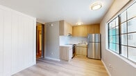 Located at 201 W Blacklidge Dr in Tucson, Arizona, this thoughtfully updated one-bedroom unit offers a clean, modern aesthetic across a single floor. Light wood laminate flooring runs throughout the entire space, creating a warm and cohesive look that ties each room together.

The living area serves as the entry point of the unit, featuring a natural wood-framed front door, a wall-mounted air conditioning unit, and a window that allows natural light to filter in. The neutral gray walls provide a versatile backdrop suitable for a variety of interior styles.

The kitchen area is neatly integrated into the layout, showcasing light wood cabinetry, a white countertop, and essential appliances, offering an efficient and stylish cooking space.

The spacious primary bedroom accommodates generous furnishing options and flows directly into a dedicated closet area featuring a striking floor-to-ceiling built-in storage system. The closet includes a large white paneled wardrobe alongside an open wood shelving unit, providing both concealed and display storage. A sliding wood-panel door adds a contemporary touch to the bedroom's entrance.

A bathroom with warm wood vanity cabinetry and a round mirror is conveniently accessible from the bedroom area. Throughout the unit, clean white baseboards and smooth walls reflect a refreshed, move-in-ready condition.