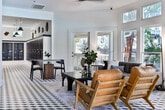 Located at 1000 Shadowood Pkwy SE in Atlanta, Georgia, this single-floor amenity space is thoughtfully designed to offer a dynamic and inviting environment for residents. The space is unified by a striking black-and-white geometric tile floor that creates a bold visual identity throughout.

The game room serves as a central focal point, featuring a sleek pool table beneath a sculptural multi-arm chandelier. A wall-mounted flat-screen TV and a folding glass garage-style door open the room to views of the outdoor pool area, flooding the space with natural light and a seamless indoor-outdoor connection.

Adjacent to the game room, the lounge area is bright and airy, with soaring ceilings and an abundance of windows that invite abundant natural light and lush outdoor greenery views. Comfortable seating — including a tufted sofa and mid-century modern leather chairs — is arranged around a coffee table, creating an ideal setting for relaxation or casual conversation. French doors provide direct access to the exterior.

A gallery-style corridor connects the main areas, lined with framed abstract artwork and a warm wood credenza, adding a curated, artistic touch. The hallway leads to a mailroom area, completing the functional layout of this well-appointed community amenity space.