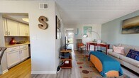 Located at 1175 Pinellas Point Dr S in Saint Petersburg, FL, this one-bedroom, one-bathroom residence offers a thoughtfully organized single-floor layout with a warm coastal aesthetic. Light gray luxury vinyl plank flooring runs throughout, complementing the soft, muted wall tones and textured ceilings found in each room.

The living room serves as the heart of the home, featuring seafoam-green accent walls and natural light from a large window. The open layout connects seamlessly to the dining area, providing a comfortable flow for daily living and entertaining.

The kitchen is efficiently designed with crisp white cabinetry, light-toned countertops, stainless steel appliances including a dishwasher, and a deep sink. A dedicated pantry with open shelving sits just adjacent, providing excellent storage and organization.

The bedroom offers a comfortably scaled retreat with a sliding glass door that brings in natural light and outdoor views of the surrounding greenery. Three closets distributed throughout the unit ensure ample storage. The bathroom features a full tub-shower combination with clean, white tile finishes.

Coastal-themed artwork and accents — including heron paintings, nautical décor, and ocean-inspired textiles — lend the space a relaxed, beach-inspired character well-suited to Florida living.