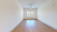 Located at 900 Great Forest Way in Oakwood, Georgia, this single-story, one-bedroom, one-bathroom unit offers a thoughtfully designed layout with contemporary finishes throughout. The open-concept living and kitchen area serves as the heart of the unit, where warm hardwood-style flooring extends across a bright, airy space. The kitchen is a standout feature, showcasing dark wood cabinetry, stainless steel appliances—including a French door refrigerator, range, microwave, and dishwasher—and a generous granite-topped island with pendant lighting overhead, providing both additional prep space and a casual dining option. The living area benefits from natural light and a ceiling fan for added comfort. The bedroom is a well-proportioned retreat finished with plush carpet, a ceiling fan, and two windows offering pleasant outdoor views of surrounding greenery. Direct access to a dedicated walk-in closet with wire shelving provides practical storage. The bathroom features a granite-topped vanity with dark wood cabinetry, hardwood-style flooring, and a shower. Clean white walls and consistent finishes throughout give the unit a cohesive, modern aesthetic.