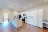 Located at 17715 Cypress Dr in Omaha, Nebraska, this well-appointed single-floor residence offers three bedrooms, two bathrooms, and a thoughtfully designed layout across a comfortable footprint. The open-concept kitchen and living area serves as the heart of the home, showcasing crisp white shaker cabinetry, a subway tile backsplash, granite countertops, stainless steel appliances including a refrigerator, range, and microwave, and a central island with a double sink and pendant lighting. Warm wood-style flooring flows throughout the main living areas, adding a cohesive and polished look. The primary bedroom offers a generous amount of space with a window that brings in natural light, while the additional bedrooms feature plush carpeting and windows with outdoor views. Three closets—including a spacious walk-in with wire shelving—provide ample storage throughout. The bathrooms are finished with white cabinetry, granite-topped vanities, matte black fixtures, and a tub/shower combination. A dedicated in-unit laundry room with full-size washer and dryer adds everyday convenience. Neutral tones and clean finishes throughout give the space a bright, move-in-ready feel.