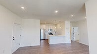 Located at 101 Groveway Loop in Sanford, North Carolina, this single-floor, one-bedroom, one-bathroom residence offers a thoughtfully designed layout that makes efficient use of its space. The open-concept kitchen and living area serves as the heart of the home, featuring rich hardwood-style flooring, recessed lighting, and large windows that invite abundant natural light and views of the surrounding neighborhood. The kitchen is well-appointed with crisp white cabinetry accented by matte black hardware, a white subway tile backsplash, quartz countertops, stainless steel appliances including a refrigerator, range, and microwave, and a peninsula with a built-in sink and pendant lighting overhead. The living area flows seamlessly from the kitchen, offering a bright and versatile space with a glass-paned exterior door. The bedroom is a comfortable retreat finished with soft carpeting, multiple windows with blinds, and a ceiling fan with light fixture. A dedicated closet provides convenient storage. The bathroom features a tub-shower combination with white subway tile surround and stylish matte black fixtures, complemented by wood-look flooring. A utility room rounds out the floor plan, adding practical functionality to this clean, modern residence.