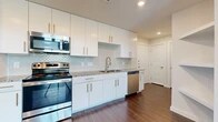 This well-appointed 2-bedroom, 2-bathroom residence offers a thoughtfully designed single-level layout with modern finishes throughout. The kitchen serves as a centerpiece of the home, showcasing white shaker-style cabinetry with gold hardware, granite countertops, a decorative scalloped tile backsplash, and a full suite of stainless steel appliances including a range, over-the-range microwave, and dishwasher. Dark hardwood-style flooring runs consistently throughout the space, creating a cohesive and polished aesthetic.

The primary bedroom features notably elevated ceilings with crown molding detail and large windows that allow abundant natural light while offering outdoor views. A second bedroom includes a ceiling fan, a double-door closet, and a window overlooking the outdoors. Both rooms offer a clean, neutral palette ideal for personalization.

The two bathrooms are finished with granite-topped white vanities and dark hardwood-style flooring. One bathroom includes a full soaking tub with a tiled surround accented by teal tile inlay. The second bathroom features a wide vanity with dual sinks and a well-lit mirror.

An entrance foyer with a paneled front door provides a welcoming arrival experience, and the open connection between the kitchen and living area enhances the overall sense of space and flow.