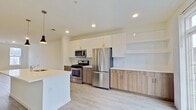 This contemporary apartment in Cherry Hill, NJ, offers 1270 square feet of thoughtfully designed living space across two floors. The lower level boasts 750 square feet, while the upper level provides 520 square feet. The home features two bedrooms, including a spacious 150 square foot primary bedroom, and three full bathrooms.

The open-concept living area is characterized by its abundance of natural light, courtesy of large windows that offer views of the surrounding area. Light-toned wood-look flooring extends throughout, complementing the crisp white walls and creating a bright, airy ambiance. A modern staircase with sleek railings connects the two levels, adding visual interest to the space.

The kitchen is a highlight, showcasing a blend of white upper cabinets and wood-toned lower cabinets, stainless steel appliances, and ample counter space. It opens to the living area, ideal for entertaining. The bathrooms feature contemporary fixtures, including glass-enclosed showers and modern vanities.

Additional amenities include a dedicated laundry room with full-sized washer and dryer, two closets for storage, and a hallway connecting the various spaces. The apartment's design emphasizes functionality and style, creating a comfortable and inviting living environment.