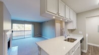 This single-floor residence at 1203 Deerfield Pkwy in Buffalo Grove, Illinois offers a thoughtfully designed open-concept layout. The kitchen serves as a central feature, equipped with white shaker-style cabinetry, light quartz countertops, a double-basin stainless steel sink, and a full suite of stainless steel appliances including a refrigerator, electric range, built-in microwave, and dishwasher. Wood-look vinyl plank flooring runs throughout the kitchen, providing a clean, durable surface that complements the white cabinetry.

The kitchen flows seamlessly into a spacious living area finished with soft blue-toned carpet and neutral gray walls. A large sliding glass door floods the living space with natural light and opens onto a private balcony with views of surrounding greenery. Recessed lighting enhances the open feel of this shared space.

The bedrooms are carpeted and generously proportioned, with windows offering natural light and outdoor views. At least one bedroom features a dedicated walk-in closet with built-in shelving. The bathroom is finished with wood-look tile flooring, a white vanity with storage, and a tub-shower combination with white tile surround and a curved chrome curtain rod, presenting a clean, modern aesthetic throughout.