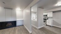 This thoughtfully designed 2-bedroom, 1-bathroom residence offers a clean, modern aesthetic across its single floor. The open-concept layout connects the living room and kitchen, creating a cohesive and functional flow. Wood-look plank flooring runs throughout the main living areas, complemented by neutral gray walls and crisp white trim.

The kitchen is a standout feature, equipped with white shaker-style cabinetry, white quartz countertops, a gray subway tile backsplash, and a full suite of stainless steel appliances including a refrigerator, electric range, and microwave. A peninsula with an undermount sink and track lighting overhead adds both practicality and style. An in-unit washer is also present.

The living room is spacious and bright, with a front entry door flanked by windows that allow natural light to filter in. Both bedrooms are carpeted and outfitted with ceiling fans. The primary bedroom is generously sized and includes a dedicated closet. The second bedroom features a sliding closet door and pendant lighting.

The bathroom is well-appointed with a white vanity, quartz countertop, and a tub/shower combination surrounded by gray subway tile. Wood-look flooring ties the bathroom design to the rest of the home. A hallway connects all rooms efficiently, completing this well-organized and move-in-ready residence.