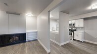 This thoughtfully designed 2-bedroom, 1-bathroom residence offers a clean, modern aesthetic across its single floor. The open-concept layout connects the living room and kitchen, creating a cohesive and functional flow. Wood-look plank flooring runs throughout the main living areas, complemented by neutral gray walls and crisp white trim.

The kitchen is a standout feature, equipped with white shaker-style cabinetry, white quartz countertops, a gray subway tile backsplash, and a full suite of stainless steel appliances including a refrigerator, electric range, and microwave. A peninsula with an undermount sink and track lighting overhead adds both practicality and style. An in-unit washer is also present.

The living room is spacious and bright, with a front entry door flanked by windows that allow natural light to filter in. Both bedrooms are carpeted and outfitted with ceiling fans. The primary bedroom is generously sized and includes a dedicated closet. The second bedroom features a sliding closet door and pendant lighting.

The bathroom is well-appointed with a white vanity, quartz countertop, and a tub/shower combination surrounded by gray subway tile. Wood-look flooring ties the bathroom design to the rest of the home. A hallway connects all rooms efficiently, completing this well-organized and move-in-ready residence.