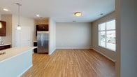 This single-floor residence offers a thoughtfully designed layout that balances functionality and comfort throughout. The open-concept living and dining area is anchored by warm hardwood-style flooring that extends into the kitchen, creating a cohesive and inviting atmosphere. Natural light filters in through a window fitted with horizontal blinds, enhancing the airy feel of the space.

The kitchen is a standout feature, showcasing rich dark-brown cabinetry, a classic white subway tile backsplash, and a full suite of stainless steel appliances, including a range, microwave, and refrigerator. A spacious island with a light countertop and pendant lighting above serves as both a prep area and a casual gathering spot.

The bedrooms are finished with plush wall-to-wall carpeting and neutral-toned walls, each offering a window with blinds for natural light and privacy. The rooms provide a calm, comfortable retreat.

Two full bathrooms serve the residence. One features a shower-tub combination, while the other offers a walk-in shower. Both include dark wood vanities topped with granite-style countertops and hardwood-style flooring.

A dedicated laundry room with side-by-side washer and dryer units and built-in wire shelving adds significant practical value to the home, rounding out this well-equipped and move-in-ready space.