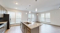 Located on Cheshire Bridge Road NE in Atlanta's vibrant 30324 corridor, this 2-bedroom, 2-bathroom residence offers a thoughtfully designed single-level layout. Light wood-look flooring flows seamlessly throughout, complemented by crisp white walls and a clean, modern aesthetic. The open-concept kitchen and living area serves as the heart of the home, anchored by a large center island topped with granite countertops and fitted with a deep single-basin sink. Pendant lighting hangs above the island, while stainless steel appliances, gray shaker-style cabinetry, and a classic subway tile backsplash complete the kitchen. An abundance of windows floods the adjacent living and dining area with natural light, and a ceiling fan adds comfort to the spacious living zone, which also features a glass sliding door. Both bedrooms are generously sized, each with ceiling fans, wood-look flooring, and natural light from well-positioned windows. The primary bedroom is notably spacious and connects to a private bathroom featuring granite-topped vanity, gray cabinetry, and a tiled shower. A hallway leads to a second full bathroom, two closets, and an in-unit laundry area, ensuring a practical and well-organized floor plan throughout.