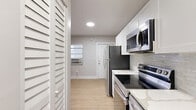 Located at 1315 NE Miami Ct in Miami, FL, this efficiently designed one-bedroom, one-bathroom unit offers a well-organized layout across a single floor. Light wood-tone vinyl flooring runs throughout the space, providing a clean, cohesive aesthetic that enhances the bright, neutral palette of soft gray walls and crisp white trim.

The kitchen is thoughtfully appointed with white shaker-style cabinetry, light stone countertops, and a full suite of stainless steel appliances including a refrigerator, electric range, and over-the-range microwave. A subway-style tile backsplash adds a subtle decorative touch, while louvered closet doors offer additional storage access nearby.

The bedroom is a comfortable, well-proportioned space featuring a window that brings in natural light and a dedicated closet with bifold doors, providing practical storage. The room's simple, clean design makes it highly adaptable.

The bathroom is a standout feature, finished with floor-to-ceiling marble-look tile surrounding the tub-shower combination, a modern floating wood-toned vanity, and a small window that provides natural ventilation. The overall finish level is polished and contemporary.

The unit also includes an in-unit laundry area with a stacked washer and dryer, adding everyday convenience. The space presents a practical and updated living option in Miami's vibrant urban core.