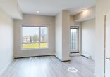 Located at 10506 121 Avenue NW in Edmonton's Eastwood neighbourhood, this efficiently designed single-floor unit offers a clean, contemporary aesthetic throughout. The open-concept living area is bathed in natural light from large windows that frame views of the surrounding cityscape and greenery, with light-toned hardwood-style flooring and neutral wall tones creating a bright, airy atmosphere.

The modern kitchen is a standout feature, showcasing crisp white upper cabinetry paired with dark lower cabinets for a striking two-tone contrast. Stainless steel appliances — including an electric range, over-the-range microwave, dishwasher, and refrigerator — are complemented by quartz countertops and a classic subway tile backsplash in soft grey. A double stainless steel sink with a contemporary arc faucet adds both style and practicality. Recessed lighting illuminates the space effectively.

The bathroom is finished in neutral tones with tile flooring and a full tub-shower combination, accented by tile trim detailing and chrome fixtures, offering a clean and functional design.

A connecting hallway provides a smooth flow between spaces. Throughout the unit, the consistent use of light flooring, recessed lighting, and a muted colour palette creates a cohesive and inviting environment well-suited to modern urban living.