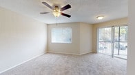 This single-story residence offers a practical and comfortable layout spread across several well-defined rooms. The living area is generously sized, featuring neutral-toned carpet, a textured ceiling, and a ceiling fan with integrated lighting. Vertical blinds cover a large window, and a sliding glass door provides access to an outdoor area, allowing natural light to fill the space.

The bedrooms share a similar aesthetic, each finished with plush carpet, neutral walls, textured ceilings, and ceiling fans. Windows in each room bring in natural light and offer views of surrounding greenery, contributing to a bright and airy atmosphere.

The kitchen is equipped with warm wood cabinetry, granite-style countertops, and includes a range, over-the-range microwave, dishwasher, and refrigerator. Light wood-look flooring runs throughout the kitchen, adding warmth and easy maintenance.

Two bathrooms serve the unit, both featuring tub and shower combinations and wood-look flooring. One bathroom includes a vanity with granite-style countertops, a large mirror, and warm wood cabinetry, while the second is more compact with a window for natural ventilation and light.