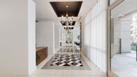 This sophisticated lobby space makes an immediate impression with its striking design elements and refined aesthetic. The grand entrance corridor is anchored by a bold black-and-white diamond-patterned tile inlay that draws the eye through the length of the space, contrasting beautifully with the polished white tile flooring throughout. Overhead, ornate dark coffered ceiling details frame a series of elegant crystal and glass chandeliers, adding a dramatic sense of height and grandeur.

A warm walnut reception desk with a chevron wood veneer serves as a welcoming focal point near the entry, complemented by curated sculptural artwork in vivid teal and gold tones displayed on the surrounding walls. The lounge areas are thoughtfully appointed with plush velvet barrel chairs, a sleek navy tufted daybed, and a glass-top coffee table, creating inviting seating vignettes throughout the open floor plan.

Floor-to-ceiling windows dressed in sheer white curtains flood the space with natural light while offering expansive views of a beautifully landscaped outdoor courtyard, complete with a pool and manicured greenery. Large-scale abstract paintings in blue and gold tones add an artistic layer to the bright, white walls. The overall ambiance is one of modern luxury with classic touches — a polished, gallery-like environment that is both welcoming and visually captivating.