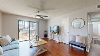 This single-story, 2-bedroom, 1-bathroom residence offers a thoughtfully designed layout that maximizes comfort and functionality. Rich hardwood flooring flows throughout the main living areas, creating a warm and cohesive aesthetic. The living room is bright and inviting, featuring a ceiling fan with integrated lighting and sliding glass doors that open to an outdoor balcony, allowing for natural light and outdoor views. Adjacent to the living area, the dining space is defined by a textured accent wall and pendant lighting, adding a touch of character. The galley-style kitchen is efficiently designed with ample white cabinetry, granite-look countertops, a subway tile backsplash, and black and stainless steel appliances, including a range, refrigerator, and dishwasher. The primary bedroom offers a comfortable, carpeted retreat with natural light from a large window, while the second bedroom features similar finishes. Three closets, including a spacious walk-in with dual hanging rods, provide generous storage throughout. The full bathroom includes a tub-shower combination with tile surround, white cabinetry, and granite-look countertops. A textured ceiling is consistent throughout the home, adding architectural detail to every room.