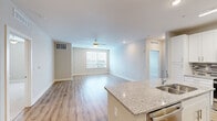 This thoughtfully designed 2-bedroom, 2-bathroom residence offers a clean, modern aesthetic throughout its single-floor layout. The open-concept kitchen and living area serves as the heart of the home, featuring warm luxury vinyl plank flooring, recessed lighting, and a ceiling fan in the living room. A large window floods the space with natural light, creating a bright and welcoming atmosphere.

The kitchen is well-equipped with crisp white shaker cabinetry, granite countertops, a mosaic tile backsplash, and a full suite of stainless steel appliances. A central island with a built-in sink provides additional prep space and casual seating, seamlessly connecting the kitchen to the living area.

Both bedrooms are generously sized and feature plush carpeting. The primary bedroom includes access to a walk-in closet outfitted with wire shelving for organized storage. The second bedroom also benefits from its own closet. One bedroom features hard surface flooring and a bright window with natural light.

The two bathrooms are finished in a neutral palette. One includes a walk-in shower with built-in shelving and wood-look vinyl flooring. Each bathroom is clean and functional in design. The overall ambiance of the residence is light, neutral, and move-in ready, with consistent modern finishes carried throughout every room.