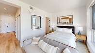 Located at 123 W Maple St in San Diego, CA, this thoughtfully designed one-bedroom, one-bathroom residence offers a compact yet highly functional layout across a single floor. The space makes excellent use of every square foot, combining contemporary finishes with a clean, modern aesthetic throughout.

The kitchen is a standout feature, showcasing bold navy-blue lower cabinetry paired with light wood upper cabinets and open shelving. Gold hardware accents add warmth, while a striking white quartz countertop with subtle veining provides ample prep space. A stainless steel gas range, built-in microwave, and full-size refrigerator complete this well-appointed culinary space, all tied together with a sleek subway tile backsplash.

The bedroom is generously proportioned and bathed in natural light from large, floor-to-ceiling windows that frame sweeping city views of the surrounding San Diego skyline. Crisp white walls and light hardwood flooring create an airy, serene ambiance throughout.

The bathroom continues the modern design language with a frameless glass walk-in shower featuring mosaic tile flooring and full-height wall tile, matte black fixtures, and navy cabinetry with gold hardware that echoes the kitchen's palette. Warm hardwood flooring extends into this space, adding continuity and comfort.

Overall, this residence delivers a refined, upscale living experience in a compact and efficient package.