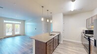 Located at 400 Katrina Court in Midlothian, Virginia, this single-floor residence offers four bedrooms and three bathrooms in a thoughtfully designed layout. The open-concept kitchen serves as a central hub, featuring a granite-topped island with an undermount sink, rich dark cabinetry, stainless steel appliances including a French door refrigerator and gas range, and stylish pendant lighting that adds a modern touch. Light wood-style flooring flows throughout the main living areas, creating a cohesive and clean aesthetic.

The living areas benefit from natural light, with one room showcasing elegant French doors that open to an outdoor view, while additional bedrooms feature large windows with exterior views. Bedrooms are finished with plush carpeting for added comfort, and the spacious primary bedroom includes an en-suite bathroom with granite countertops, dark wood cabinetry, and a dedicated walk-in shower with chrome fixtures.

The bathrooms are well-appointed with granite vanity tops and dark wood cabinetry that complement the kitchen's design language. A dedicated closet provides additional storage. Neutral tones throughout the home create a bright, welcoming ambiance well-suited to a variety of interior styles.