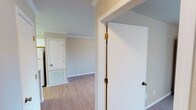 This single-floor unit offers a thoughtfully designed layout that balances functionality and comfort throughout its connected living spaces. Crown molding runs consistently through the main areas, adding a clean, finished look to the warm neutral-toned walls and light hardwood-style flooring that spans the kitchen, hallway, living, and bathroom areas.

The kitchen is well-equipped with white cabinetry featuring gold-toned trim accents, ample upper and lower storage, light countertops, a double-basin sink, a dishwasher, electric range with coil burners, and a full-size refrigerator. A peninsula counter defines the boundary between the kitchen and the open living and dining area, enhancing the sense of openness.

The living area is generously proportioned, finished with hardwood-style flooring, a ceiling fan with light fixture, and a sliding glass door fitted with vertical blinds that invites abundant natural light and provides access to an outdoor area. The transition to the hallway leads past a full bathroom, which includes a single-sink vanity with mirror, a tub/shower combination with a curtain rod, and continued hardwood-style flooring. The bedroom offers plush carpeting, a natural window, and a spacious reach-in closet with a hanging rod, completing this comfortable and practical space.