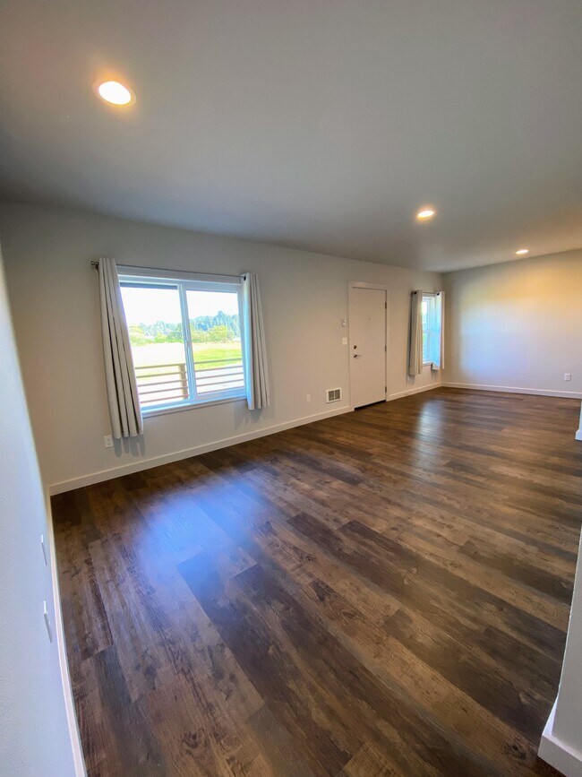Amplia sala de estar con grandes ventanales, suelo de madera oscura y luces empotradas. - 575 Greenwood Ave