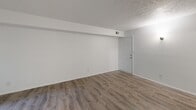 This single-floor, one-bedroom, one-bathroom unit in Indianapolis, Indiana offers a practical and efficiently arranged layout. The living room serves as the main gathering space, featuring wood-look laminate flooring, white walls, and a textured ceiling. A structural beam detail adds subtle architectural character, while a wall sconce provides supplemental lighting. The entry door opens directly into this area, creating a welcoming first impression.

The kitchen is positioned adjacent to the living area, connected via a hallway that organizes the flow of the unit. The bedroom is a well-proportioned private retreat, finished with wall-to-wall carpet for comfort and a natural light source through a standard window with views of surrounding greenery. A sliding-door closet provides dedicated storage with a clothing rod and shelf. HVAC vents are present throughout, ensuring climate control across the unit.

The bathroom includes a full-size soaking tub with an overhead shower, enclosed by clean white surround panels and outfitted with chrome fixtures. Throughout the unit, a neutral white color palette and clean finishes create a bright, straightforward living environment suited to a range of furnishing styles.