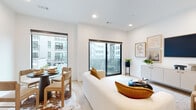 This single-floor residence offers a thoughtfully designed open-concept layout with a clean, modern aesthetic throughout. The living and dining area is anchored by large sliding glass doors that flood the space with natural light and open onto a private balcony overlooking a pool and surrounding urban courtyard. Light hardwood flooring runs continuously throughout, complementing the crisp white walls and recessed lighting that enhance the airy, contemporary atmosphere. A curated gallery wall and a streamlined credenza add warmth and character to the living space.

The kitchen is appointed with white shaker cabinetry extending to the ceiling, granite countertops, a subway tile backsplash, and a full suite of stainless steel appliances including a range, microwave, dishwasher, and refrigerator. The galley-style layout connects efficiently to the main living and dining area.

The bedroom is a calm, minimalist retreat with recessed lighting and ample wall space. The bathroom features a white shaker vanity with granite countertops, a large mirror, and matching hardwood-style flooring, maintaining the cohesive design language found throughout the residence. Overall, the unit presents a polished, modern living environment with quality finishes and practical flow.