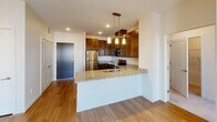 Located at 5801 Xerxes Ave N in Brooklyn Center, Minnesota, this single-floor residence offers a thoughtfully designed layout with contemporary finishes throughout. The kitchen serves as the centerpiece of the home, showcasing rich dark-stained cabinetry that extends to the ceiling for ample storage, light speckled granite countertops, and a full suite of stainless steel appliances including a refrigerator, electric range, built-in microwave, and dishwasher. A peninsula with pendant lighting above provides additional prep space and a natural transition into the open living area, which features warm hardwood-style flooring and recessed lighting. The living space is bright and welcoming, benefiting from natural light through nearby windows. Two bedrooms offer plush carpeting, generous closet space, and large windows that bring in daylight and exterior views. Both bathrooms mirror the kitchen's design aesthetic, featuring the same dark cabinetry and granite countertops, undermount sinks, large vanity mirrors with overhead lighting, and light tile flooring. The cohesive use of finishes throughout creates a polished, modern ambiance that balances comfort and style across every room of this well-appointed home.