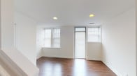 Located on Waterman Boulevard in the Central West End neighborhood of St. Louis, Missouri, this two-floor residence offers a clean, modern aesthetic with a thoughtfully designed layout across both levels. The main floor features a welcoming entryway with a classic paneled front door, intercom system, and smart thermostat. Rich hardwood-style flooring extends throughout the main living areas, complementing the crisp white walls and recessed lighting overhead. The kitchen is well-equipped with white cabinetry, dark countertops, and black appliances including a range and refrigerator. A full bathroom on this level includes tiled flooring, a tub/shower combination, and a window for natural ventilation. Upstairs, a carpeted staircase leads to the upper level, where a spacious, light-filled living area boasts multiple windows with blinds, recessed lighting, and direct access to an outdoor space. Additional rooms on the upper floor include a bedroom with plush carpeting, generous windows allowing ample natural light, and a bathroom featuring a wide vanity with dual mirrors and chrome fixtures. Throughout both floors, the design maintains a consistent, neutral palette that creates a bright and versatile living environment.
