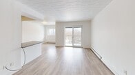 Located at 500 Glenelm Crescent in Waterloo, Ontario, this 2-bedroom, 1-bathroom unit offers a thoughtfully designed layout with modern, clean finishes throughout. Light wood-look flooring runs consistently across the space, complemented by crisp white walls and tiled ceilings that keep the interior bright and cohesive.

The open-concept kitchen, dining, and living area forms the heart of the unit. The kitchen features white cabinetry, dark countertops with a peninsula island, a stainless steel refrigerator, and a tile backsplash — providing ample prep and storage space. The living and dining area flows seamlessly from the kitchen and is bathed in natural light from dual windows and a sliding glass door that opens onto a private balcony with outdoor views.

Both bedrooms are comfortably sized with large windows that bring in natural light and overlook the surrounding neighbourhood. The primary bedroom includes mirrored sliding closet doors, enhancing the sense of space. Baseboard heating is present throughout.

The bathroom is clean and modern, featuring white subway tile surrounding a full soaker tub and shower combination, grey stone-look floor tiles, and a vanity with sink. Dark-finished interior doors with brushed hardware add a refined contrast to the otherwise light and airy aesthetic of the unit.
