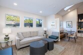 Located at 34050 Westchester Ter in Fremont, CA, this single-floor professional space offers a well-appointed and efficiently organized layout ideal for a boutique office or service-oriented business. The interior is finished in a clean, neutral palette of warm whites and soft beiges, complemented by light hardwood flooring throughout, creating a calm and welcoming ambiance.

Upon entry, a comfortable reception and waiting area greets visitors with a plush sofa, accent seating in teal and gray tones, and paired ottomans arranged over a textured area rug. A row of windows along the front wall floods the space with abundant natural light and offers pleasant views of the surrounding greenery. Recessed lighting further brightens the interior.

A casual dining or breakout nook features built-in banquette seating with a colorful upholstered back, two round tables, and additional chairs — an inviting spot for informal meetings or staff use. Windows here also frame outdoor views of mature trees, reinforcing the connection to the outdoors.

The conference room is a standout feature, with a full-length glass partition wall, a substantial wood conference table, and upholstered seating for multiple guests. High ceilings in this area add an sense of openness. Two private offices provide focused work environments, each finished with clean lines and ample workspace. The overall design balances professionalism with approachable warmth.
