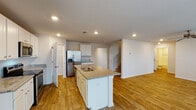 This two-story home in Pensacola, Florida offers generous living space across five bedrooms and three full bathrooms, designed with a clean, neutral aesthetic throughout. Wood-look plank flooring runs consistently through the main living areas, bedrooms, and bathrooms, lending a cohesive and low-maintenance quality to the interior.

The main level centers around an open-concept layout connecting the kitchen and living area. The kitchen is well-appointed with white shaker-style cabinetry, granite-look countertops, stainless steel appliances including a refrigerator with ice maker, electric range, and microwave, and a central island with a double sink. Recessed lighting illuminates the space efficiently. The adjacent living area features a ceiling fan, large windows, and French doors that invite natural light and provide outdoor access.

The bathrooms are finished with white vanities, granite-look countertops, and wood-look flooring. One bathroom includes a soaking tub, while another features a walk-in shower area. Bedrooms are bright and well-sized, with natural light from windows and walk-in closets equipped with wire shelving systems. The attached garage accommodates two vehicles and includes an automatic opener. Textured ceilings are present throughout the home.