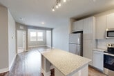 Located at 515 Dunlop Blvd SW in Madison, Alabama, this one-bedroom, one-bathroom unit offers a thoughtfully designed layout with modern finishes throughout. The open-concept kitchen and living area serves as the heart of the home, featuring a granite-topped island, crisp white cabinetry extending to the ceiling, a full suite of stainless steel appliances including a refrigerator, range, microwave, and dishwasher, and a subway tile backsplash. Track lighting illuminates the kitchen, while durable hardwood-style flooring flows throughout the main living areas, reflecting natural light from the windows.

The living area provides a comfortable, open feel with neutral gray walls and clean lines. The bedroom is carpeted for warmth and comfort, offering two windows that bring in ample natural light, along with a dedicated closet for storage. The full bathroom is well-appointed with a granite vanity, white cabinetry, a tub-shower combination with white tile surround, and hardwood-style flooring that ties the space together cohesively.

A dedicated utility room accommodates a washer and dryer, adding everyday convenience. Throughout the unit, consistent neutral tones, modern hardware, and quality finishes create a clean, contemporary ambiance suited for comfortable living.