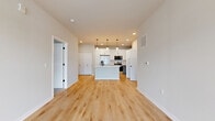 Located at 1211 Carrington Blvd in Mount Pleasant, WI, this thoughtfully designed single-floor residence offers 1,000 square feet of modern living space across 2 bedrooms and 1 bathroom. The open-concept kitchen and living area serves as the heart of the home, showcasing a large center island with a sink, crisp white upper cabinetry, gray lower cabinets, and white quartz countertops. Stainless steel appliances — including a range, microwave, and refrigerator — complete the kitchen. Stylish pendant lighting and recessed fixtures illuminate the space, while light hardwood flooring flows throughout the main living areas. An in-unit stacked washer and dryer adds everyday convenience. The primary bedroom spans 330 square feet and includes a spacious walk-in closet with built-in shelving. The second bedroom features plush carpeting and a large window offering neighborhood views. The bathroom is finished with gray cabinetry, white quartz countertops, and light wood-style flooring. Neutral tones, clean lines, and an abundance of natural light from large windows give this home a bright, contemporary ambiance. An attached garage with concrete flooring provides additional storage and parking.