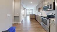 Located on Daniel Island in South Carolina, this single-floor residence at 50 Central Island St offers a thoughtfully designed open-concept layout with contemporary finishes throughout. Rich wood-look flooring flows seamlessly through the main living areas, anchoring a bright and cohesive interior.

The kitchen is a standout feature, outfitted with gray shaker-style cabinetry, a classic white subway tile backsplash, stainless steel appliances including a range, microwave, dishwasher, and refrigerator, and a undermount sink with modern fixtures. A kitchen island with pendant lighting adds both functionality and style, while a barn-style sliding door adds a charming architectural detail nearby.

The living area benefits from natural light through large windows with blinds, and a ceiling fan contributes to comfortable year-round living. The bedroom continues the warm, neutral palette with plush carpeting, crown molding, a ceiling fan, and a generous window that draws in natural light and outdoor views.

The bathroom is finished with large-format gray wall tile surrounding the soaking tub and shower, wood-look flooring, a granite-topped vanity, and a framed mirror. A built-in niche along the hallway provides additional convenience and storage. The overall ambiance is clean, modern, and move-in ready.