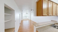 This one-bedroom, one-bathroom unit in Austin, Texas offers a well-organized single-floor layout designed to maximize functionality. Light wood-tone flooring runs consistently throughout the space, lending a cohesive and clean aesthetic across every room.

The combined kitchen and living area forms the heart of the unit. The kitchen is configured as a galley-style space with light wood cabinetry, speckled countertops, a stainless steel refrigerator, electric range, and built-in microwave. A half-wall peninsula separates the kitchen from the living area, which benefits from track lighting and an open sightline toward the living room. The living room receives generous natural light through a corner arrangement of windows fitted with horizontal blinds, and is equipped with a ceiling fan.

The bedroom is a well-proportioned private retreat with a large window that brings in additional natural light. It connects to a dedicated walk-in closet featuring dual hanging rods and built-in shelving for ample storage. The bathroom includes a glass-enclosed shower stall and is accessible via a short hallway. Built-in open shelving is also present near the entryway, offering convenient additional storage.