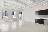 Located in the heart of Downtown Los Angeles on South Spring Street, this urban loft delivers a compelling blend of industrial character and modern finishes. The open-concept main living area is defined by soaring exposed concrete ceilings with visible structural beams and bold silver ductwork, lending an authentic loft aesthetic. Polished light-toned tile floors run throughout, reflecting natural light and enhancing the sense of openness. Large windows frame dynamic city skyline views, and a glass-panel door opens to a private balcony, seamlessly connecting the interior to the vibrant urban landscape outside.

The kitchen is thoughtfully designed with dark espresso cabinetry reaching to the ceiling, white countertops, a clean tile backsplash, and a full suite of stainless steel appliances including a refrigerator, range, microwave, and dishwasher — offering both style and practicality.

The bathroom features a full soaking tub and shower adorned with striking blue and gray mosaic glass tile, complemented by a vessel sink set on a dark vanity with a marble-toned countertop, chrome fixtures, and a large mirror — creating a spa-like retreat. The overall ambiance of the space is bright, airy, and distinctly metropolitan, ideal for those seeking an elevated Downtown Los Angeles lifestyle.