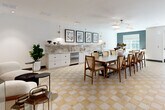 Located at 4980 Stonewall Tell Rd in Union City, GA, this thoughtfully designed single-floor amenity space offers a generous and well-appointed environment for gathering, working, and socializing. The entry hallway immediately sets an elevated tone with striking chevron-patterned hardwood flooring, steel-framed glass partitions, and curated wall art, creating a welcoming and polished first impression. Natural light filters through full-length glass entry doors, further brightening the corridor.

The living room features a bold dark accent wall, a plush sectional sofa, and contemporary pendant lighting, complemented by a signature gallery wall of graphic framed artwork. Warm-toned checkered tile flooring flows seamlessly into the combined dining and living area, where a long communal dining table anchored beneath modern pendant lights is flanked by a sleek wet bar with marble-style backsplash, stainless steel appliances, and ample cabinetry. A teal accent wall and natural window light add depth and warmth to this space.

A dedicated conference room offers a rich wood table, leather executive chairs, herringbone-patterned flooring, and a statement sputnik chandelier, ideal for professional meetings. Throughout, curated artwork, designer lighting, and a cohesive neutral palette with bold accents create a refined and inviting atmosphere.