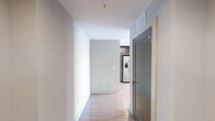 Located on the 14th floor in the heart of downtown Raleigh, this modern 1-bedroom, 1-bathroom unit offers a thoughtfully designed layout with contemporary finishes throughout. Light hardwood flooring runs continuously across the open living area, kitchen, and bedroom, creating a cohesive and airy atmosphere.

The combined kitchen and living area is a standout feature, anchored by floor-to-ceiling windows that flood the space with natural light and frame sweeping city views. A distinctive round structural column adds an architectural element to the living room, which also includes a ceiling fan. The kitchen is well-appointed with dark wood cabinetry, white quartz countertops, a subway tile backsplash, stainless steel appliances including a side-by-side refrigerator with water dispenser, electric range, microwave, and dishwasher.

The bedroom is generously sized with its own floor-to-ceiling window wall, providing continued access to natural light and urban views, along with a dedicated closet. The bathroom features a dark wood vanity with a white countertop, a large mirror, modern lighting fixtures, and a glass-enclosed walk-in shower with tile surround. A hallway connects the rooms, completing this efficiently designed urban residence.