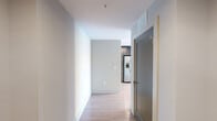 Located on the 14th floor in the heart of downtown Raleigh, this modern 1-bedroom, 1-bathroom unit offers a thoughtfully designed layout with contemporary finishes throughout. Light hardwood flooring runs continuously across the open living area, kitchen, and bedroom, creating a cohesive and airy atmosphere.

The combined kitchen and living area is a standout feature, anchored by floor-to-ceiling windows that flood the space with natural light and frame sweeping city views. A distinctive round structural column adds an architectural element to the living room, which also includes a ceiling fan. The kitchen is well-appointed with dark wood cabinetry, white quartz countertops, a subway tile backsplash, stainless steel appliances including a side-by-side refrigerator with water dispenser, electric range, microwave, and dishwasher.

The bedroom is generously sized with its own floor-to-ceiling window wall, providing continued access to natural light and urban views, along with a dedicated closet. The bathroom features a dark wood vanity with a white countertop, a large mirror, modern lighting fixtures, and a glass-enclosed walk-in shower with tile surround. A hallway connects the rooms, completing this efficiently designed urban residence.