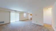Located at 20 Church Rd in Maple Shade, NJ, this single-floor residence offers a well-organized layout designed for comfortable everyday living. The living area is generously proportioned, featuring neutral wall-to-wall carpeting and a large sliding glass door fitted with vertical blinds that allows abundant natural light to fill the space while providing access to an outdoor balcony area. The open flow between the living space and kitchen makes the layout feel connected and functional. The kitchen is outfitted with warm honey-toned wood cabinetry, dark speckled countertops, a gas range, dishwasher, and refrigerator, all set on durable tile flooring. The bedrooms are carpeted and offer a calm, neutral atmosphere. Each bedroom includes a closet — one featuring a walk-in configuration — providing ample storage. The bathroom is finished with distinctive light blue ceramic wall tiles, a mosaic tile floor, a wood-framed vanity mirror, and a full bathtub, lending the space a classic character. Throughout the residence, the clean white walls and light color palette create a bright, airy ambiance. Central air vents and a thermostat are visible throughout, ensuring year-round comfort in this straightforward and functional single-level home.
