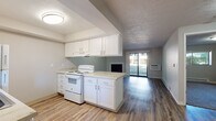 Located at 12407–12415 East 12th Ave in Spokane Valley, Washington, this single-floor unit offers a practical and comfortable layout with thoughtful finishes throughout. The kitchen is efficiently designed with white cabinetry, marble-look countertops, and a full suite of white appliances including a range, refrigerator, and dishwasher. An open pass-through peninsula connects the kitchen to the living area, promoting an airy, connected feel across the space. The living room is a standout area, featuring a classic fireplace as a focal point and a full-width sliding glass door that fills the room with natural light and provides direct outdoor access with views of the surrounding greenery. Wood-look vinyl plank flooring runs throughout the main living areas, offering both durability and a modern aesthetic. The bedroom is carpeted for comfort and includes a window with outdoor views and a baseboard heating system. The bathroom is clean and functional, complete with a soaking tub, grab bar, vanity, and additional baseboard heating. A built-in pantry provides practical storage. Neutral wall tones and textured ceilings lend a consistent, understated style throughout the unit, making it a move-in-ready space in a convenient Spokane Valley location.