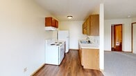 Located at 2311 Massillon St in Findlay, Ohio, this one-bedroom, one-bathroom unit offers a practical and well-organized layout across a single floor. The galley-style kitchen is efficiently designed with warm oak cabinetry above and below the counter, a stainless steel sink, white electric range with overhead microwave ventilation, and a full-size refrigerator. Durable hardwood-style flooring runs throughout the kitchen, lending a clean and cohesive look.

The bedroom is comfortably sized, finished with plush wall-to-wall carpeting, and features a ceiling fan with light fixture for year-round comfort. A large sliding-door closet provides ample storage, while a window with blinds allows natural light and outdoor views. A second view of the bedroom reveals an open doorway connecting to the hallway, reinforcing the straightforward, accessible flow of the unit.

The bathroom continues the hardwood-style flooring and includes a full-size tub and shower combo with white surround, a toilet, and a towel bar. A hallway connects all rooms, contributing to the unit's efficient and functional design. Neutral wall tones and consistent warm wood trim details throughout give the space a cohesive, tidy aesthetic well-suited for comfortable everyday living.