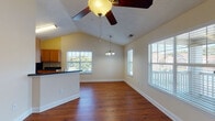Located at 950 Parkside Dr in Clayton, NC, this two-story home is designed with an open, airy feel accentuated by vaulted ceilings and rich hardwood flooring that flows consistently throughout the space. The main living and dining area is generously proportioned, benefiting from multiple windows that flood the room with natural light. A ceiling fan overhead and a pendant light fixture above the dining space add functional character, while a vibrant red exterior door provides direct access to the outdoors.

The kitchen features warm wood cabinetry paired with dark countertops and is equipped with stainless steel appliances, including a range and over-the-range microwave. A breakfast bar separates the kitchen from the living area, creating a natural and convenient transition between spaces.

The bathrooms are finished with wood-toned cabinetry and dark granite-style countertops, complemented by large mirrors and hardwood flooring. One bathroom includes a bathtub and direct access to a walk-in closet, while another provides convenient proximity to in-unit laundry. The bedrooms feature vaulted ceilings, ceiling fans, ample closet space with built-in shelving, and large windows that bring in plenty of natural light.