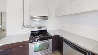 Located on Beverly Boulevard in the heart of Los Angeles, this single-floor unit offers a versatile and open layout ready for customization. Throughout the main living and flex areas, bare concrete floors give the space an industrial character, complemented by bright white walls and flush-mount ceiling lighting. The open rooms are generously proportioned, with one area featuring a wall-mounted heating unit and exposed utility conduits that add to the raw, urban aesthetic. Natural light filters in through window blinds in one room, while French doors in another open to the exterior, enhancing the sense of openness and providing indoor-outdoor connectivity. The kitchen is outfitted with stainless steel appliances, including a gas range with a stainless hood, a dishwasher, dark cabinetry, and a white subway tile backsplash that keeps the space clean and functional. In sharp contrast to the minimalist living areas, the bathroom is a bold standout, clad floor-to-ceiling in dramatic black marble tile with striking white veining, paired with a white soaking tub and toilet for a sleek, high-contrast look. This space presents a unique opportunity for a variety of uses in a prime Los Angeles location.