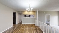 This single-story, 3-bedroom, 3-bathroom home offers a thoughtfully designed layout that balances comfort and functionality. The entry foyer features rich, dark wood-look flooring and an elegant chandelier, creating a welcoming first impression. The open living area is accented by a ceiling fan, a classic tiled fireplace, and a window that brings in natural light, all set over plush neutral carpeting. A stepped transition leads toward the kitchen area, adding architectural interest to the common spaces. The generously sized primary bedroom includes a ceiling fan, soft carpeting, and access to a spacious walk-in closet outfitted with built-in shelving and hanging rods on dark wood-look flooring. The two additional bedrooms are carpeted, each equipped with ceiling fans and built-in closets, providing ample storage. All three bathrooms feature marble-style tiled tub-shower combinations, with at least one showcasing wood-look flooring and granite-style countertops for an elevated finish. A dedicated hallway connects the bedrooms and living spaces efficiently. Throughout, the home maintains a consistent neutral color palette, textured ceilings, and clean white trim, contributing to a cohesive and move-in-ready aesthetic.