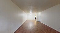 This 690 square foot, single-floor apartment offers a thoughtful layout maximizing space and functionality. The primary bedroom, measuring 170 square feet, provides a comfortable retreat with a built-in closet for storage. The living area boasts sleek wood flooring that extends throughout, creating a cohesive and warm ambiance. Large windows in both the living room and bedroom flood the space with natural light, while offering views of the surrounding area.

The kitchen, though compact, is efficiently designed with ample cabinetry in a light wood finish, contrasting nicely with white countertops and appliances. A unique feature is the skylight above, bringing additional brightness to the cooking space. The bathroom, while not pictured, likely continues the modern aesthetic with clean lines and white fixtures.

The open-concept layout seamlessly blends the living and dining areas, ideal for entertaining or relaxing. The neutral color palette of white walls and ceilings contributes to a sense of spaciousness and allows for personalization through decor. Overall, this apartment presents a well-designed, low-maintenance living solution in a contemporary style.