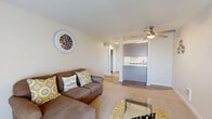 Located in Lynnwood, WA, this well-designed one-bedroom, one-bathroom unit offers a thoughtful layout across a single floor. The open living room is bright and inviting, featuring plush carpeting, a ceiling fan with light fixture, and a large sliding glass door fitted with vertical blinds that floods the space with natural light. The kitchen is a standout feature, designed in a galley style with light gray cabinetry, marble-look countertops, wood-look vinyl flooring, and black appliances including a range, dishwasher, and refrigerator. A pass-through opening connects the kitchen to the living area, enhancing the open feel of the home. The bedroom offers a comfortable, carpeted retreat with a window providing views of the surrounding area and ample natural light. Two closets provide generous storage throughout the unit. The bathroom is clean and functional, featuring a full tub-shower combination with a white surround. With a neutral color palette of warm whites and soft beiges throughout, the space maintains a cohesive, welcoming ambiance well-suited for comfortable everyday living.