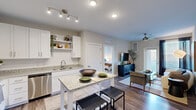 Located at 5101 Attain Centre Dr in Fredericksburg, VA, this thoughtfully designed 2-bedroom, 3-bathroom residence offers a functional single-floor layout with modern finishes throughout. The open-concept kitchen is a standout feature, showcasing white shaker cabinetry, granite countertops, stainless steel appliances including a refrigerator, range, and microwave, and a central island with bar seating — ideal for both meal prep and casual dining. Hardwood-style flooring runs through the main living areas, lending warmth and cohesion to the space. The living room is bright and inviting, with a ceiling fan, a glass-panel door providing natural light and outdoor access, and ample room for comfortable seating arrangements. Both bedrooms are carpeted and feature windows that allow natural light to filter in. The primary bedroom offers a cozy, well-proportioned retreat with natural light. The three bathrooms are finished with granite-top vanities, white cabinetry, and tiled tub-shower combinations. A dedicated hallway and closet provide additional storage and organization. The overall color palette of soft grays and whites creates a clean, contemporary ambiance throughout the home.